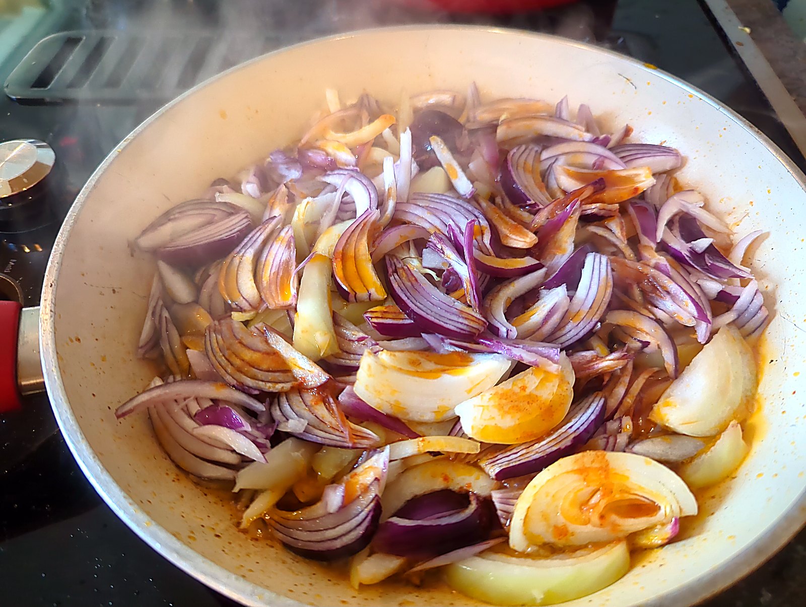 La mjaddara, ou comment j'ai séduit ma conjointe avec du riz, des lentilles et une boîte de tomates image Oignons rouges et jaunes émincés au début de la cuisson, dans l'huile orangée récupérée de la sauce.