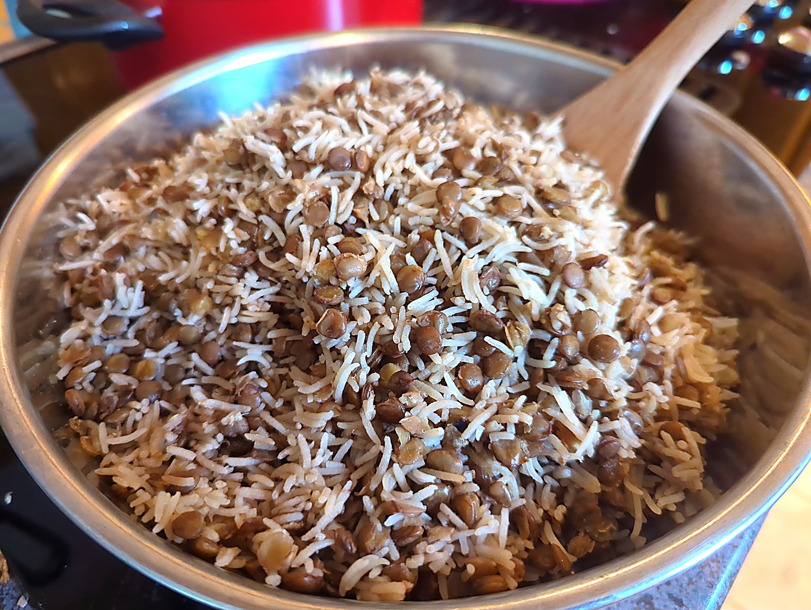 La mjaddara, ou comment j'ai séduit ma conjointe avec du riz, des lentilles et une boîte de tomates image Riz basmati et lentilles brunes cuits ensemble dans une casserole, mélangés à la cuillère de bois.
